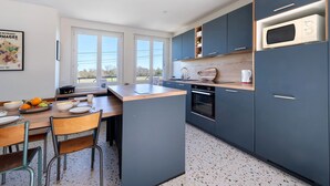 Una cocina moderna con una isla central, muebles oscuros y un microondas.