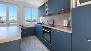 Una cocina moderna con armarios oscuros, encimera de madera, horno empotrado y ventana con vistas al exterior.