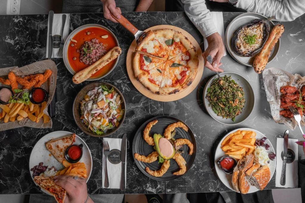 Una mesa de comedor con diversos platos, incluyendo pizza, ensalada y pan.