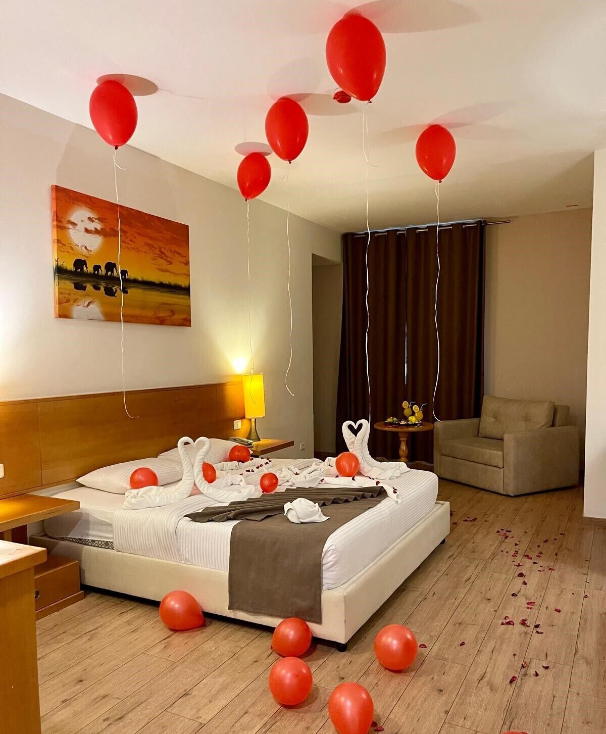 A hotel room with a bed, a nightstand, a lamp, a painting, and a sofa.