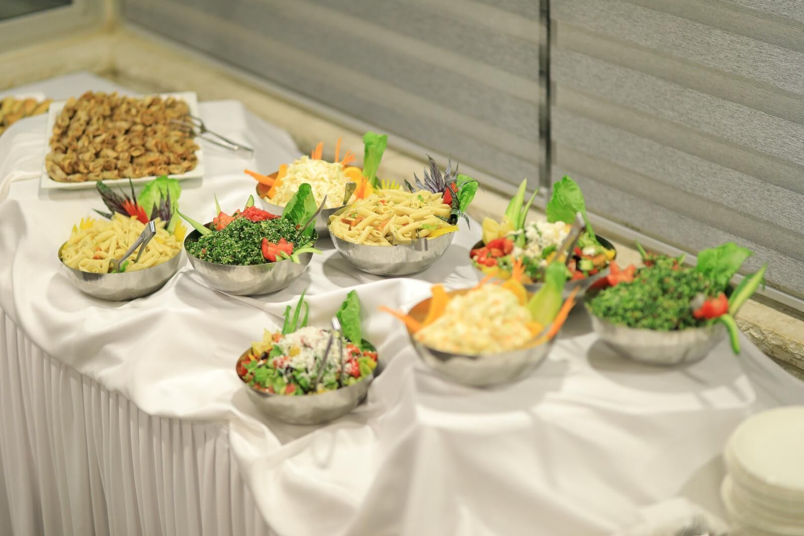 Une table de buffet proposant divers plats, notamment des pâtes, des salades et des légumes.