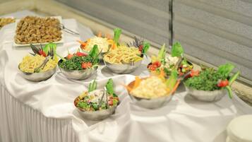 Une table de buffet proposant divers plats, notamment des pâtes, des salades et des légumes.