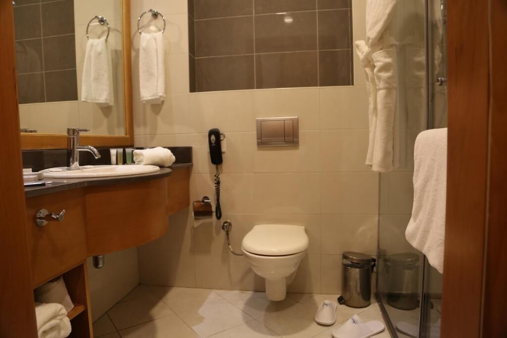 Ein Badezimmer mit Toilette, Waschbecken, Spiegel und Duschbereich.
