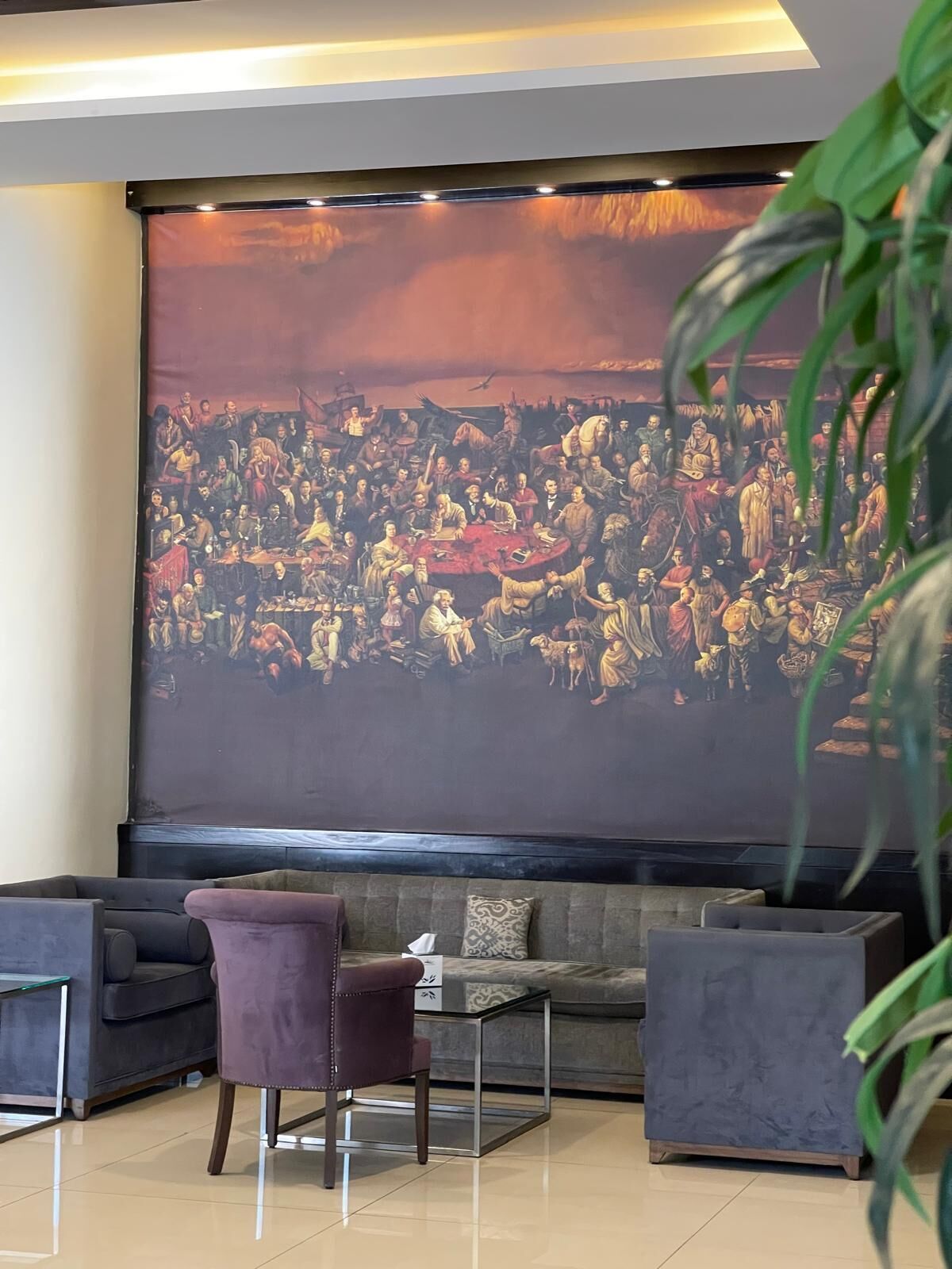 Une pièce dotée d’un grand écran de projection sur lequel est affiché un tableau historique, ainsi que d’un canapé, d’un fauteuil et d’une petite table.