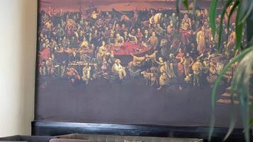 Une pièce dotée d’un grand écran de projection sur lequel est affiché un tableau historique, ainsi que d’un canapé, d’un fauteuil et d’une petite table.