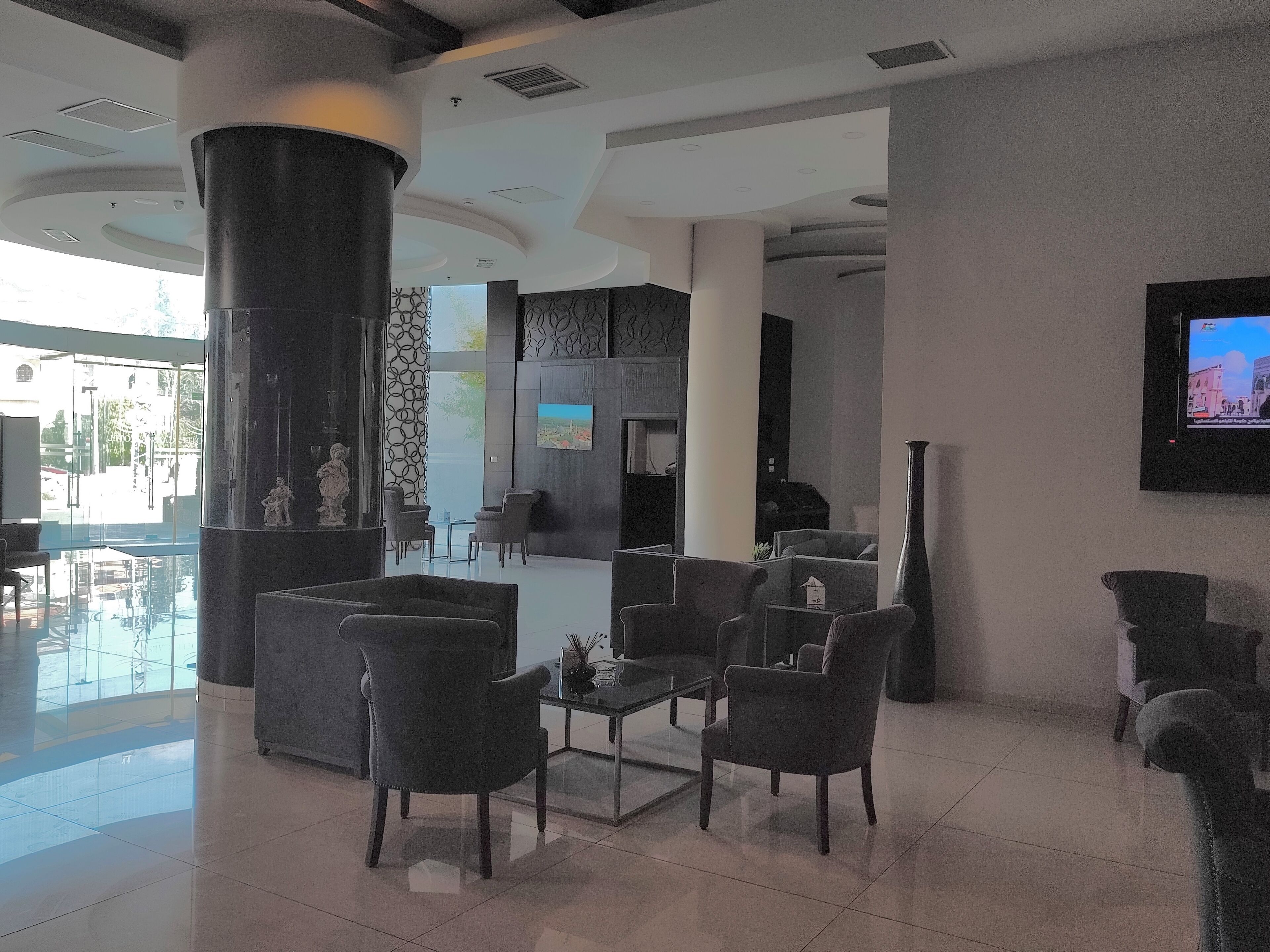 A modern lobby with a seating area, a large pillar, and a television screen.