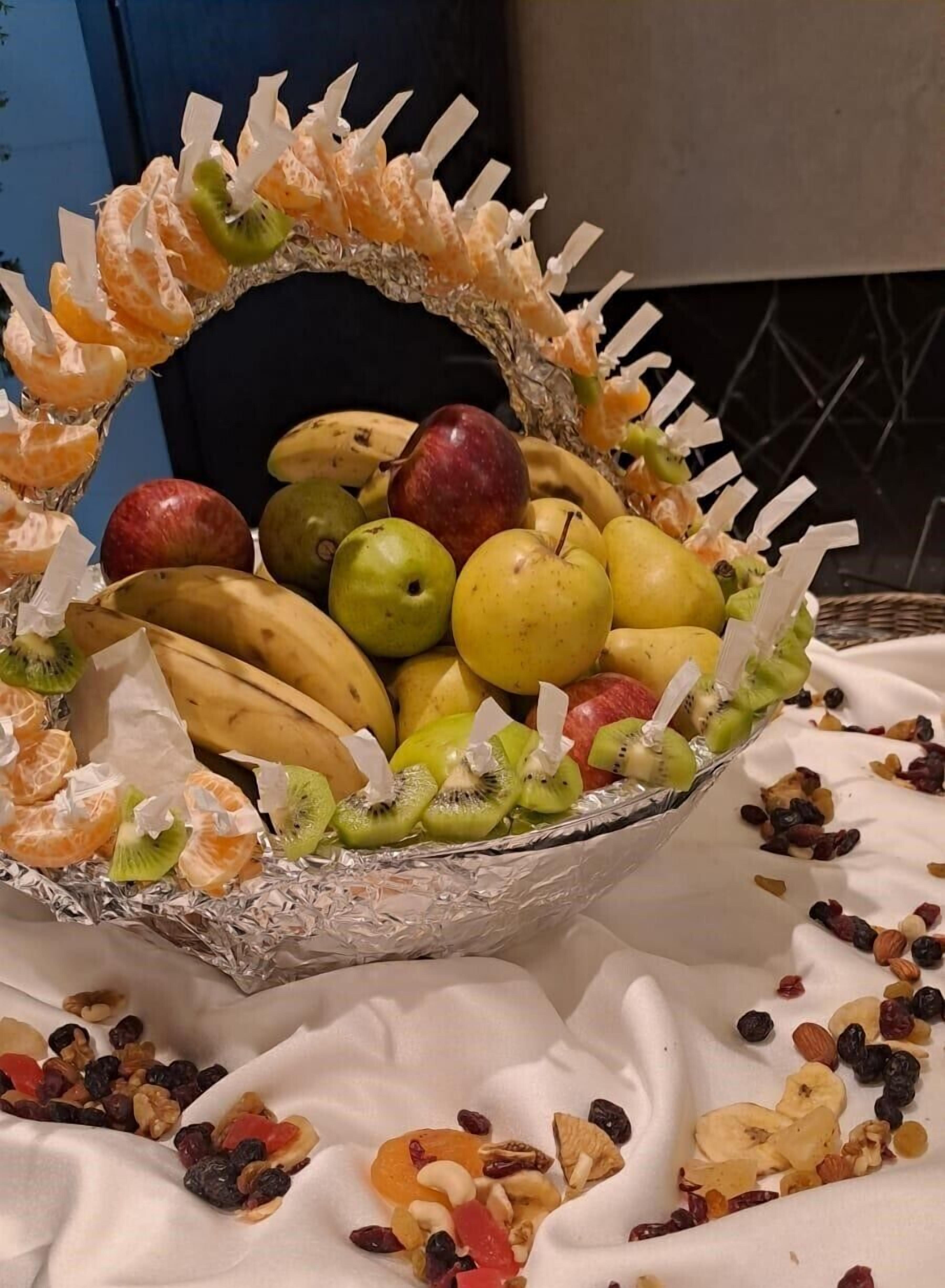 A fruit basket with oranges, kiwis, bananas, apples, pears, and nuts.