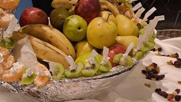 A fruit basket with oranges, kiwis, bananas, apples, pears, and nuts.
