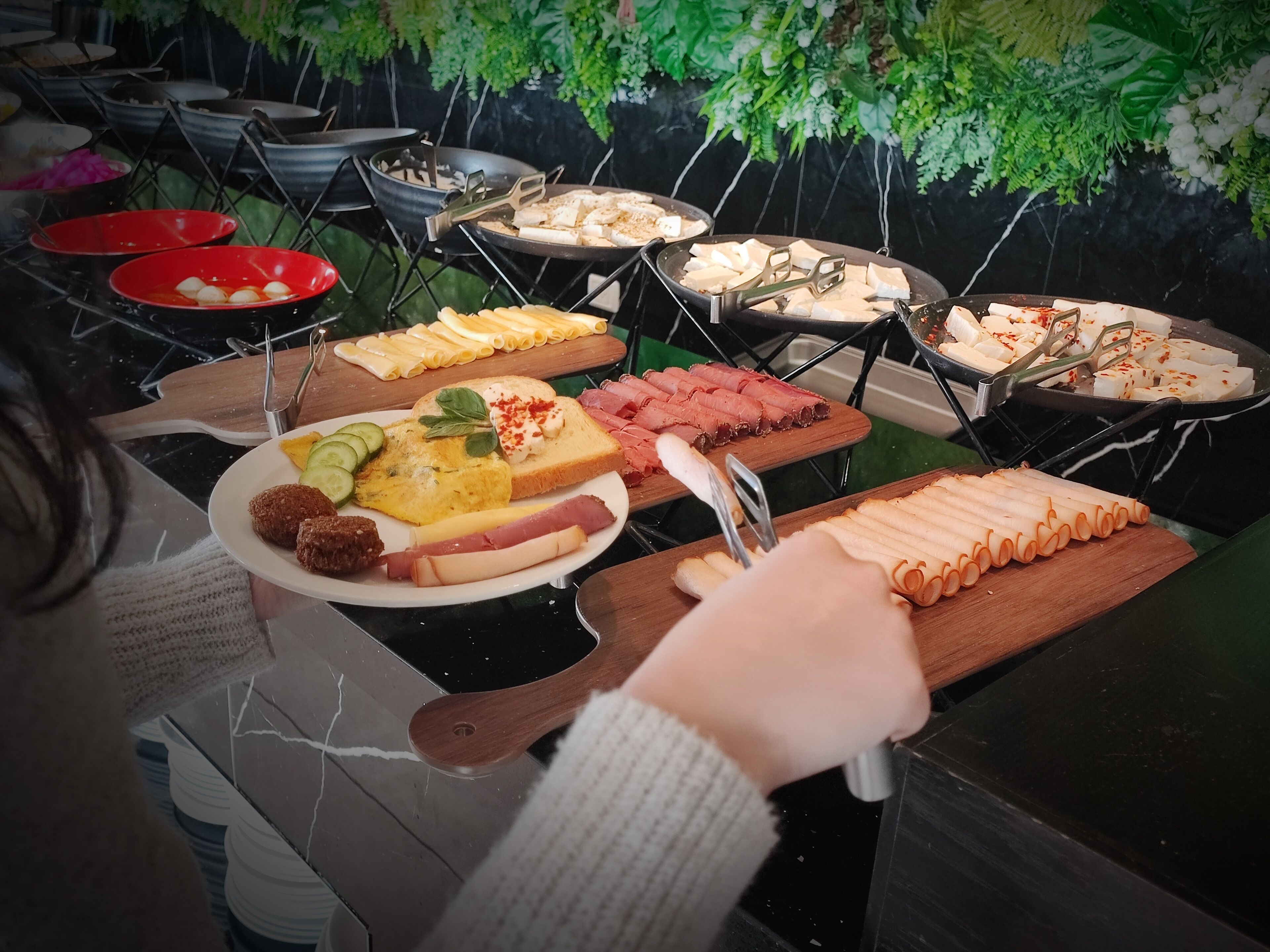 Un buffet proposant une variété de plats, notamment des fromages, des viandes et des légumes.