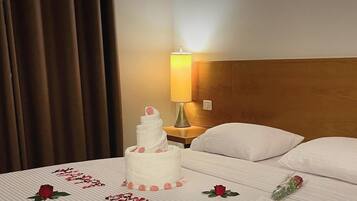 A hotel room with a bed, a nightstand, a lamp, and a cake with 'Happy Birthday' written on it.