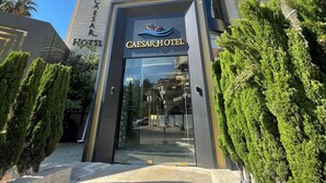 A modern hotel with a curved facade, a prominent entrance, and palm trees in the foreground. - Caesar Hotel (Ramallah)