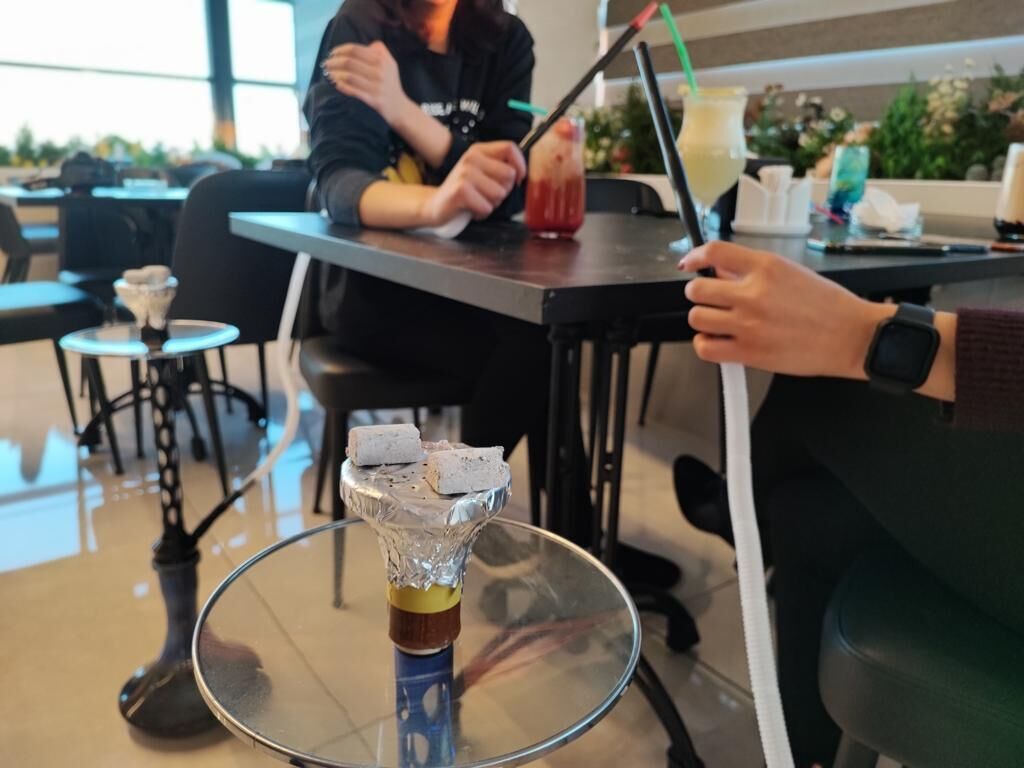 Een glazen tafel met een drankje en een waterpijp.