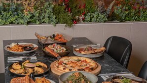 A dining table with various dishes, a cityscape view, and a Caesar Hotel logo. - Caesar Hotel (Ramallah)
