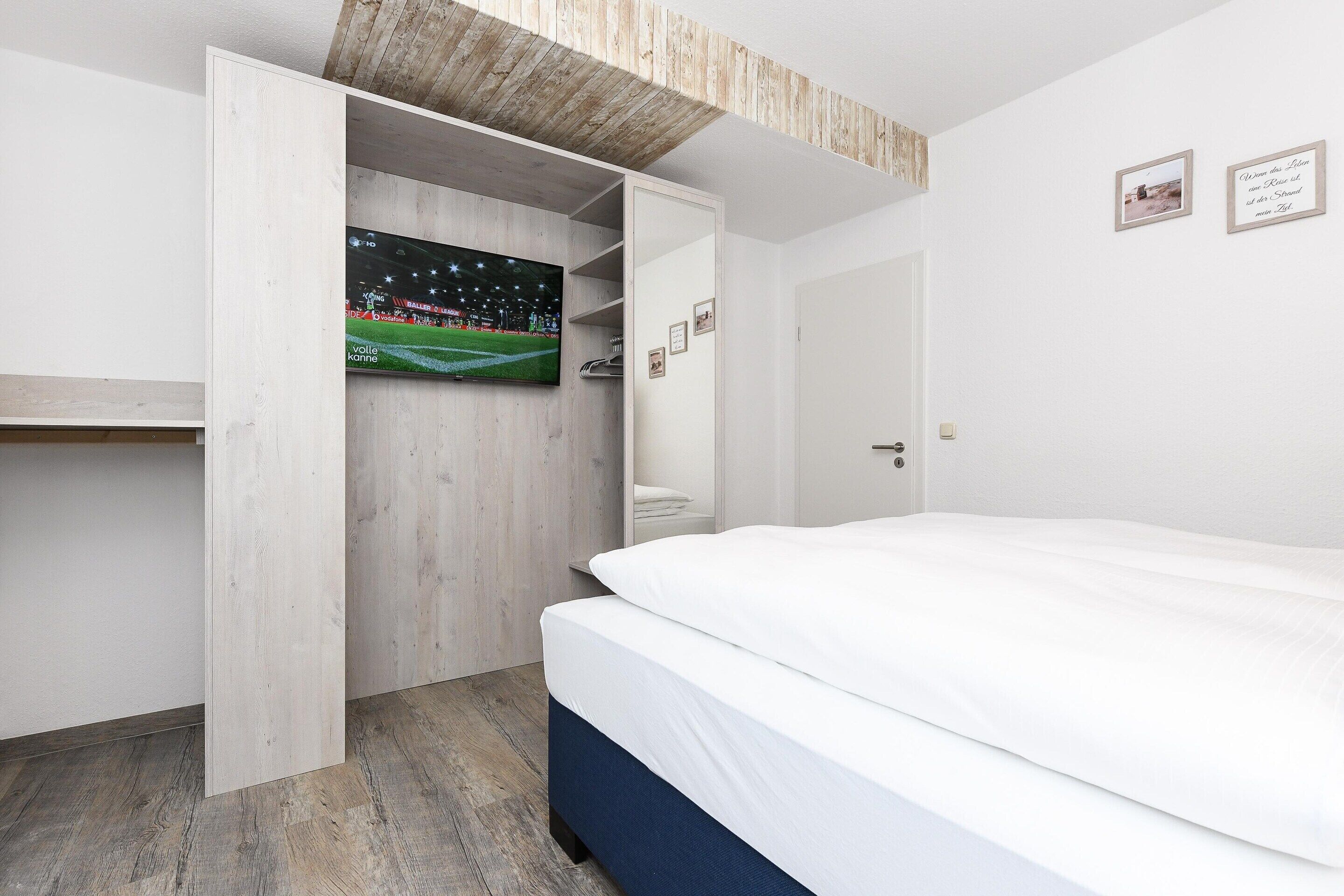 Una camera da letto con un letto, un armadio e una televisione appesa al muro.