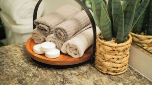A bathroom with a marble countertop, a woven basket holding rolled towels, and a potted aloe plant. - The Emerald Escape 2BR/2BA King Suite (Hermiston)