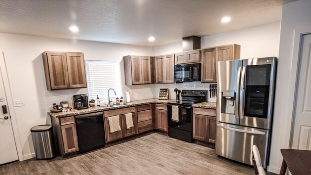 A modern kitchen with wooden cabinets, stainless steel appliances, and a granite countertop. - The Emerald Escape 2BR/2BA King Suite (Hermiston)