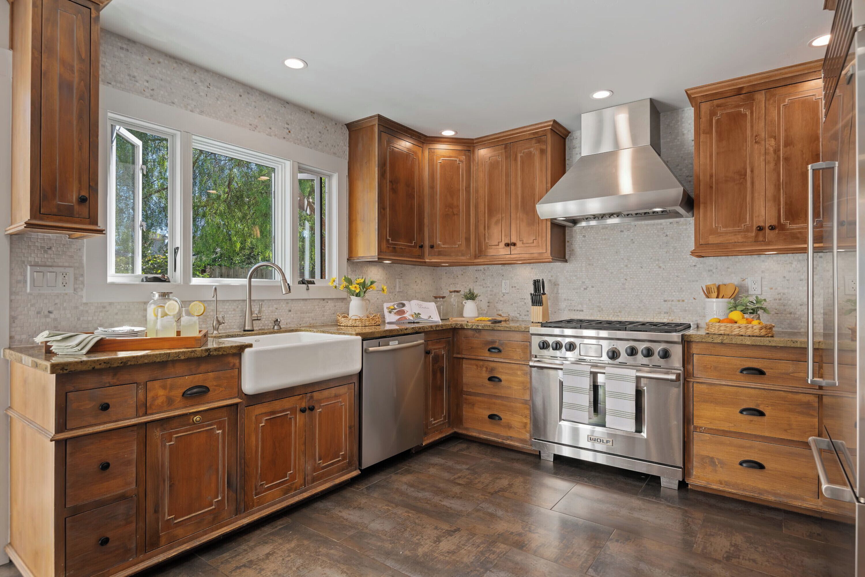 A kitchen with wooden cabinets, a stainless steel range hood, a dishwasher, and a built-in oven.