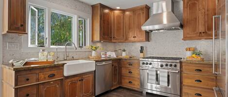 A kitchen with wooden cabinets, a stainless steel range hood, a dishwasher, and a built-in oven.
