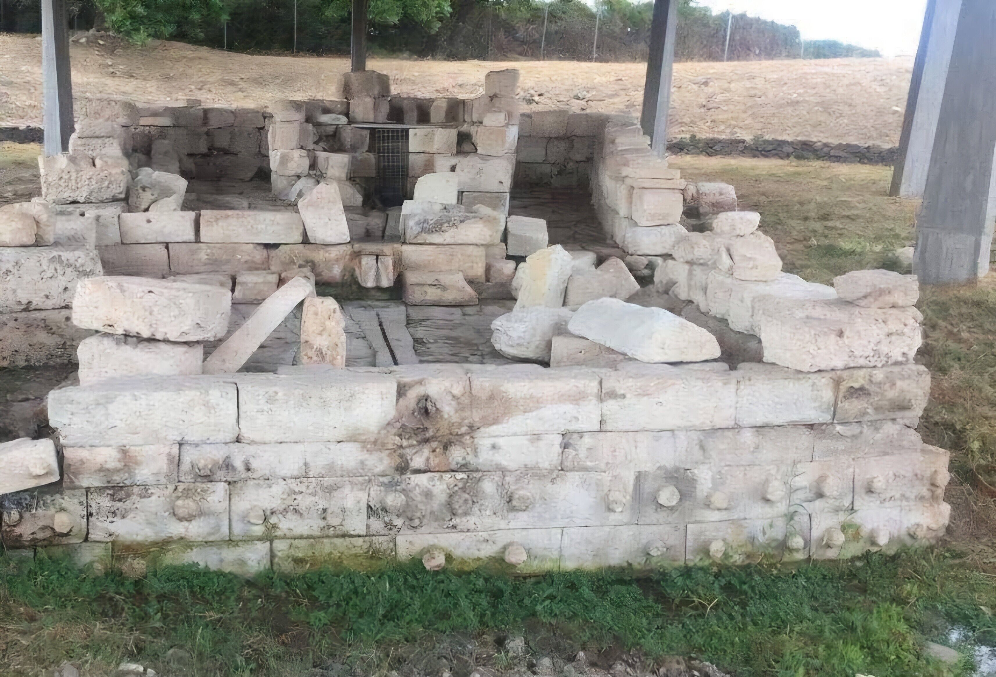 Een oud stenen bouwwerk met een centrale opening, omgeven door onregelmatige blokken steen.