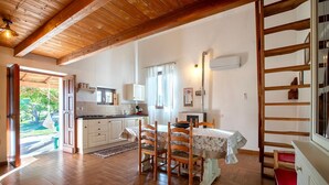 A kitchen with wooden beams, white cabinets, a dining table with chairs, and a view through an open door. - Holiday Home 'Domo Clelia' with Private Terrace, Garden & Air Conditioning (Nulvi)