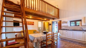 A kitchen with a wooden staircase, a dining table with chairs, and a kitchen counter. - Holiday Home 'Domo Clelia' with Private Terrace, Garden & Air Conditioning (Nulvi)