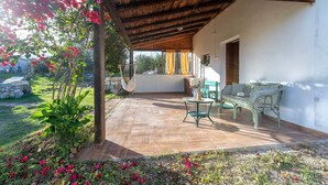 An outdoor patio with a wooden ceiling, a green sofa, and a table. - Holiday Home 'Domo Clelia' with Private Terrace, Garden & Air Conditioning (Nulvi)