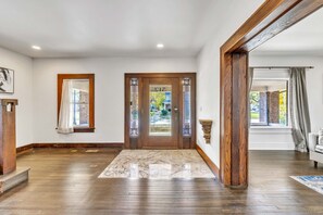 Ein geräumiger Flur mit Marmorboden, einer Holztür mit Glasfeldern und Blick ins Freie durch ein Fenster.