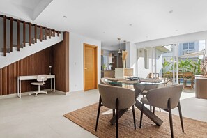 Un interior moderno con una zona de comedor, una escalera y vistas al exterior.