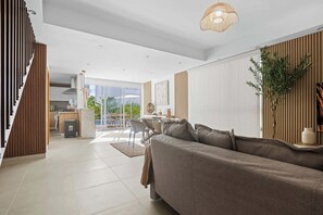 Una sala de estar moderna con sofá, comedor, cocina y una escalera.