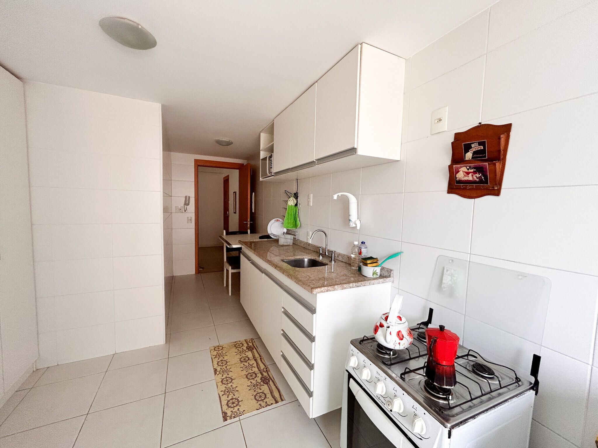 Une cuisine de taille réduite, équipée d’une cuisinière à gaz, d’un évier et d’un plan de travail.