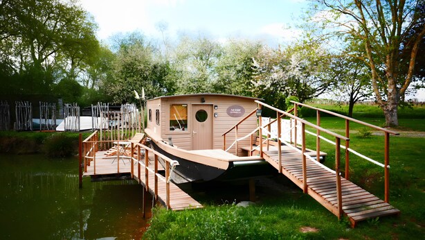 Ein Hausboot mit Deck, einem kleinen Wohnkabinett und einer Treppe zum Wohnbereich.