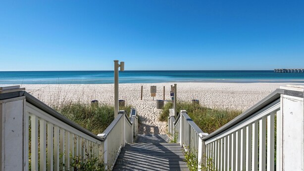 A wooden staircase leading to a beach with a clear blue sky. - ☀️Panoramic Gulf and Pool Views-Steps to Beach-Calypso 3-1006☀️ (Panama City Beach)