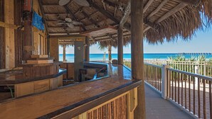 A wooden deck with a thatched roof overlooking a beach. - ☀️Panoramic Gulf and Pool Views-Steps to Beach-Calypso 3-1006☀️ (Panama City Beach)
