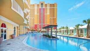 A swimming pool with lounge chairs and a building with balconies in the background. - ☀️Panoramic Gulf and Pool Views-Steps to Beach-Calypso 3-1006☀️ (Panama City Beach)