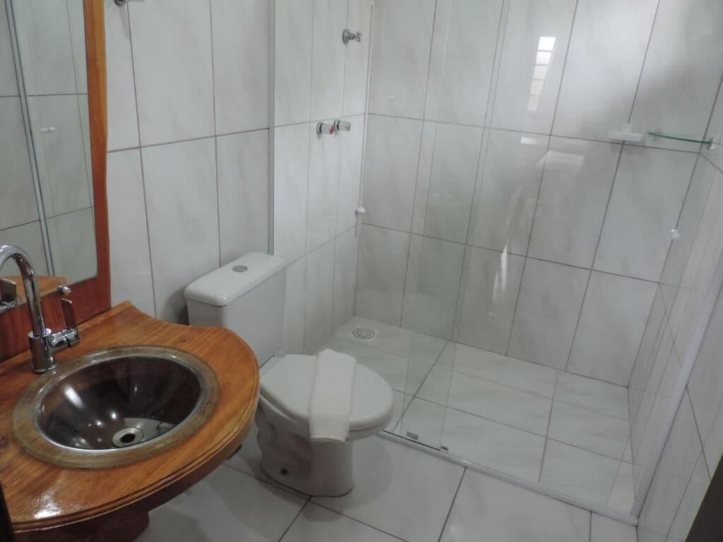 Ein Badezimmer mit Holzwaschtisch, Waschbecken, Toilette und einer Duschkabine aus Glas.