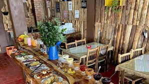 A buffet setup with various food items and a plant centerpiece. - Cabanas Costaneira  (Cambará do Sul)