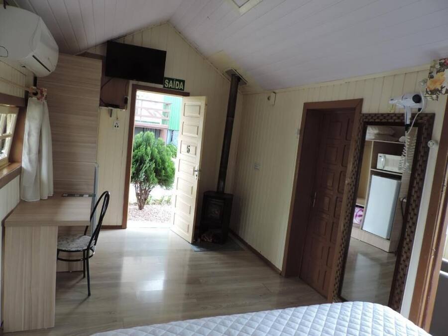 A room with a bed, a desk, a chair, a stove, and a door leading outside.