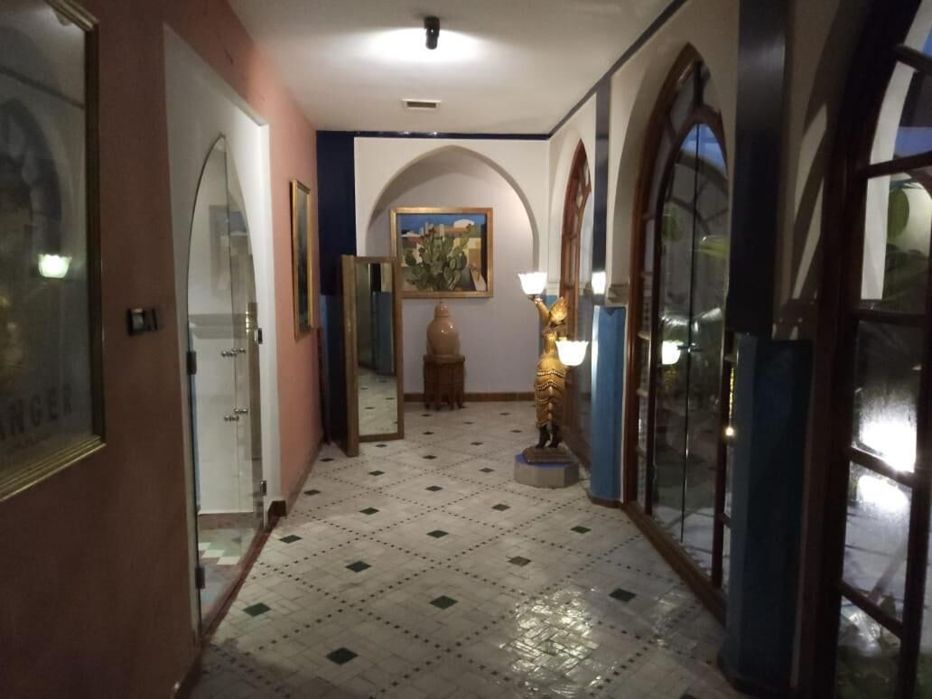 Ein Flur mit Fliesenboden, einer Statue, einem gerahmten Gemälde und einer Tür mit Fensterteil.