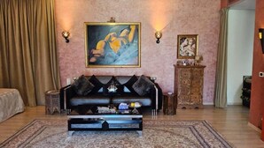 Un salon avec un canapé, une table basse, un tableau et un meuble.