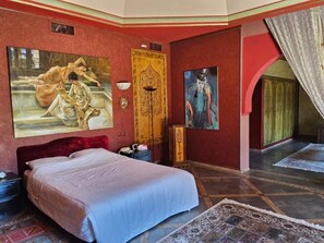 A bedroom with a large bed, a wooden wardrobe, a painting on the wall, and a patterned rug on the floor. - Villa de Luxe sur la Palmeraie de Marrak (Marrakech)