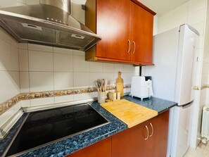 A kitchen with a Bosch induction cooktop, wooden cabinets, a white refrigerator, and a toaster.
