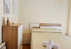 A neatly arranged bedroom with a wooden dresser, a bed with a beige quilt, and two framed motivational posters on the wall.