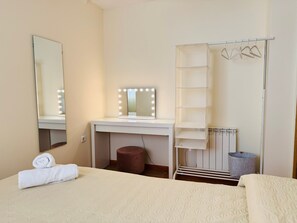 A hotel room with a bed, a vanity with a mirror and lights, a radiator, and a hanging rack. - Apartment 'Comodidad Cerca Del Centro Granada' with Shared Pool, Wi-Fi and Air Conditioning (Albolote)