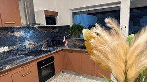 Een moderne keuken met een donker marmeren aanrechtblad, een inbouwoven en een raam met uitzicht op de omgeving.