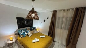 Een moderne slaapkamer met een bed, een hanglamp en een schilderij aan de muur.