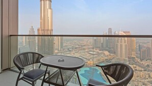 Ein Balkon mit zwei Stühlen und einem kleinen Tisch, mit Blick auf eine Skyline mit hohen Gebäuden, darunter ein markanter Wolkenkratzer.