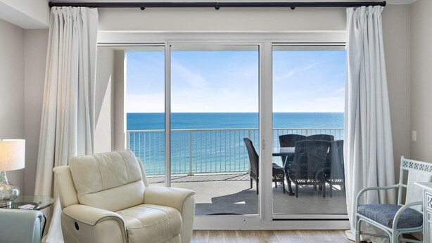 Un balcone con vista sull'oceano, una sedia bianca e un tavolo con sedie.