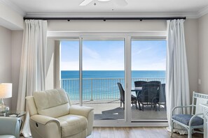 A balcony with a view of the ocean, a white chair, and a table with chairs. - Regency Isle 1009 (Orange Beach)
