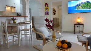 Un soggiorno moderno con zona pranzo, televisore a schermo piatto e tavolo con frutta.