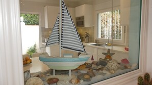 Un modellino di barca a vela in una vetrina con una cucina sullo sfondo.